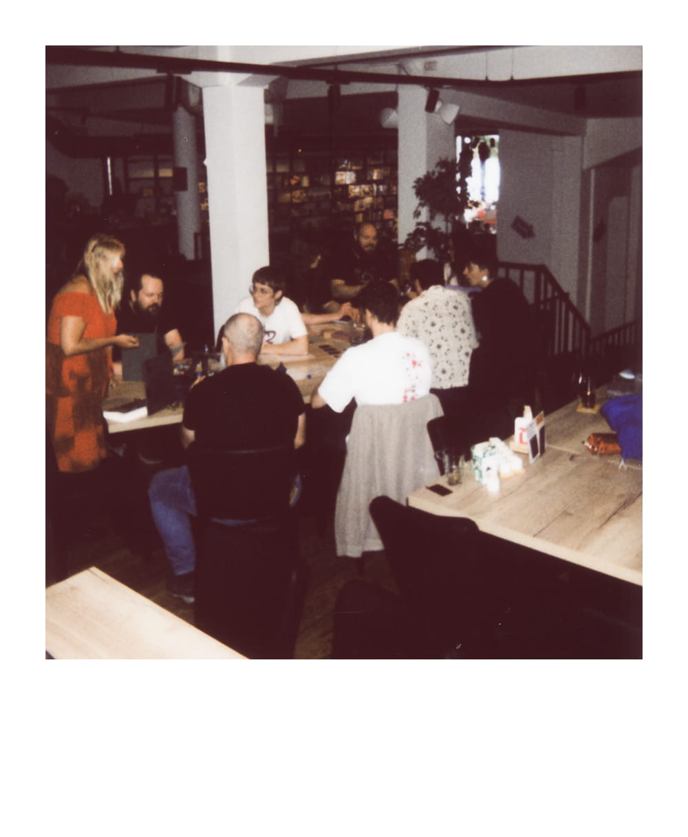A group plays a tabletop roleplaying game together around a long table in a cozy indoor venue.