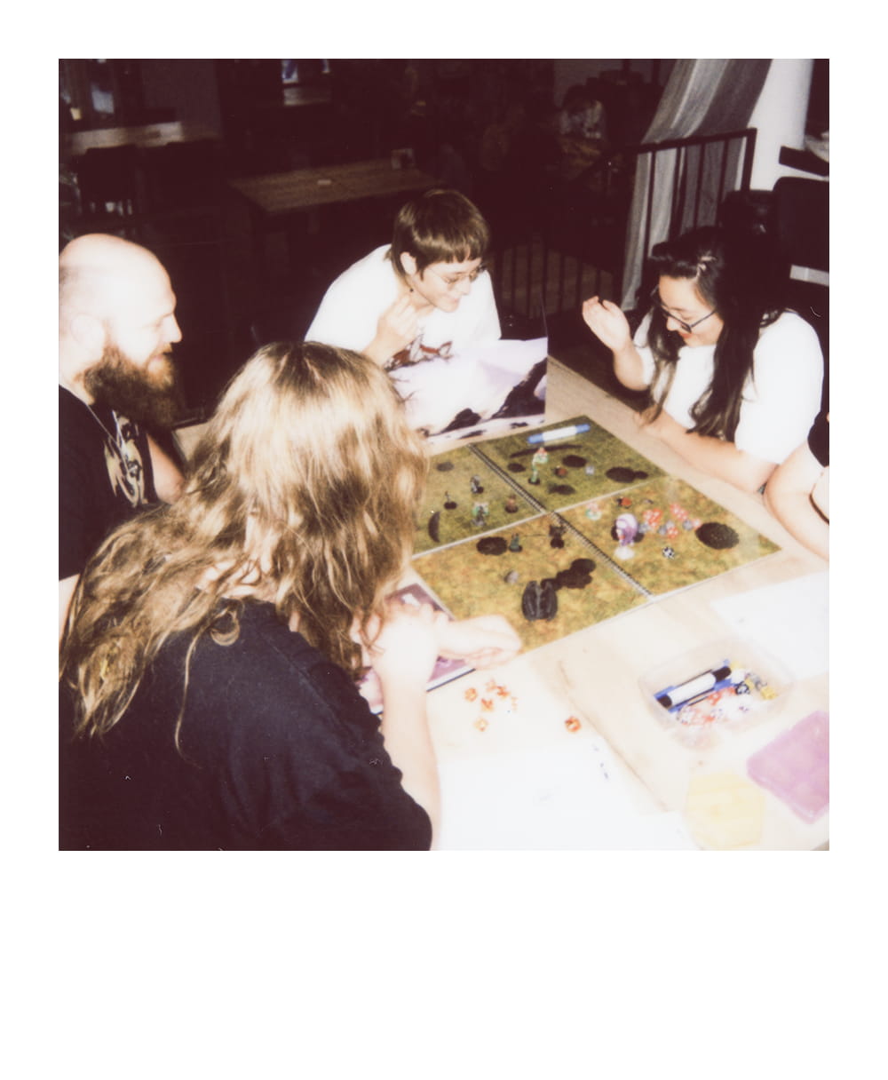 Group of tabletop roleplaying players gather around a miniature-filled battle map during a game.